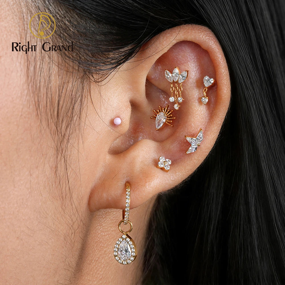 A close-up of a person's ear showcasing a multi-piece gold and silver ear cuff stack with clear rhinestones, including a teardrop dangle, sunburst, bird, flower, and heart designs. The brand logo 'Right Grand' is visible in the top left corner.