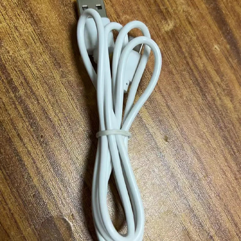 White USB cable coiled on a wooden surface