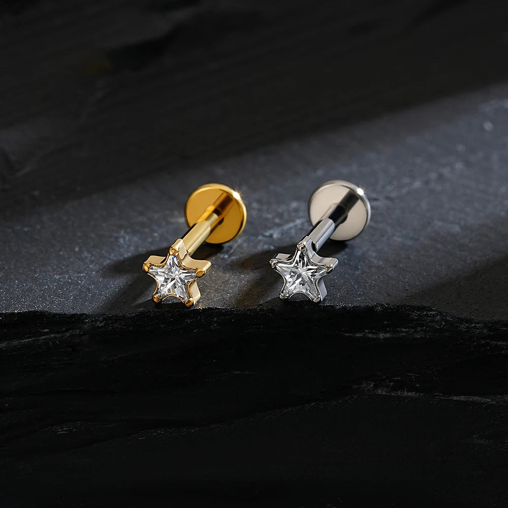 Gold and silver star-shaped earrings on a dark surface