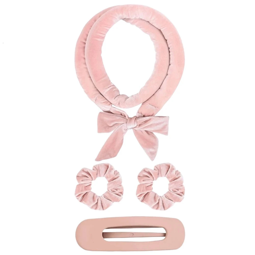Set of pink hair accessories including a headband, scrunchies, and a clip on a white background