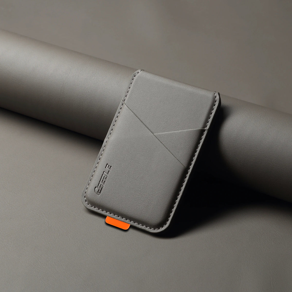 Gray leather cardholder with an orange tag on a gray surface