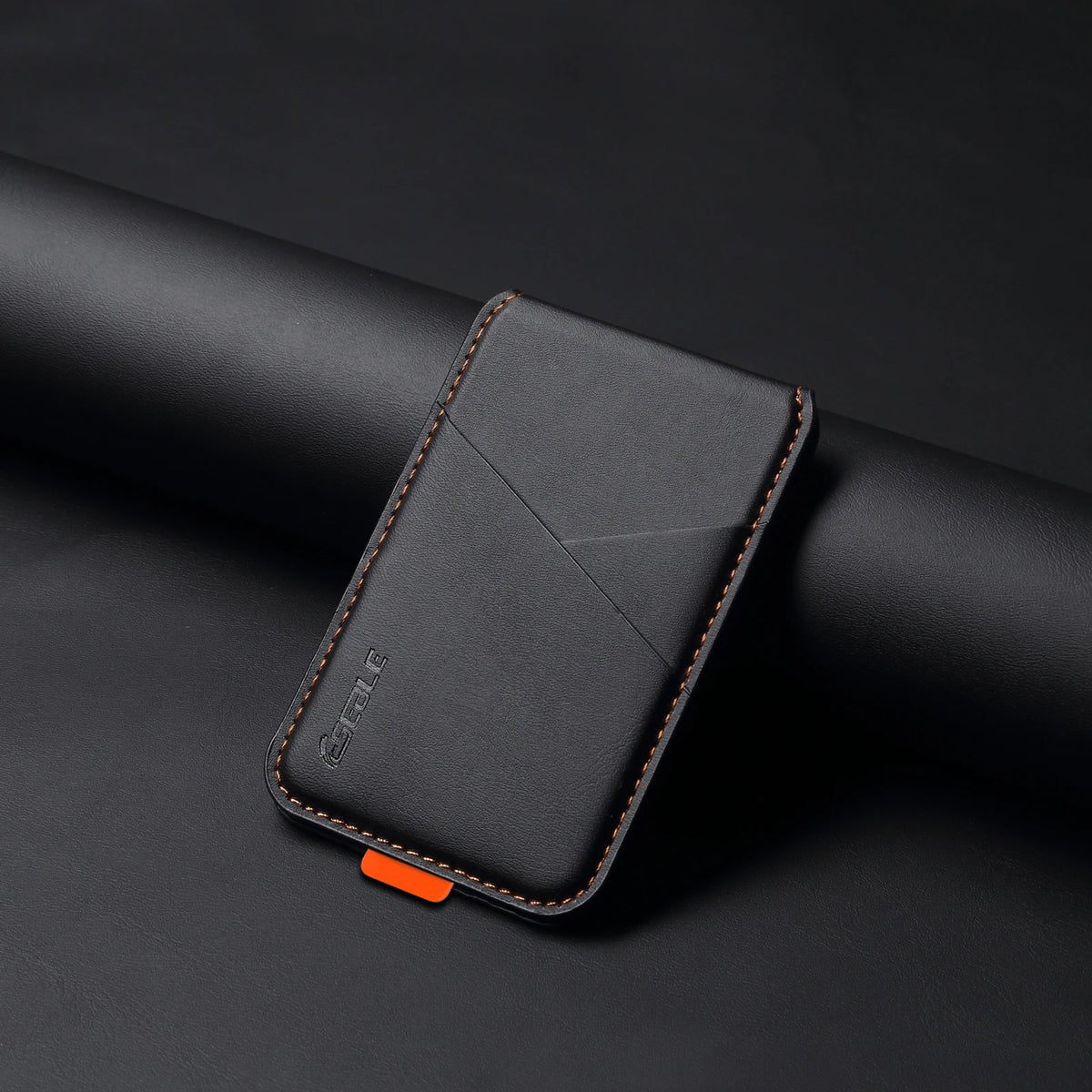 Black leather cardholder with orange accent on a dark background